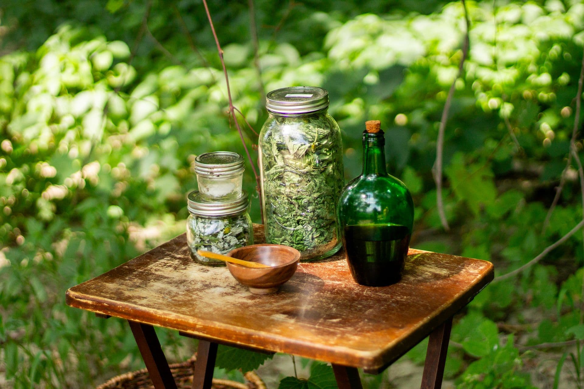 Jars of dried herbs on a small wooden table in the garden