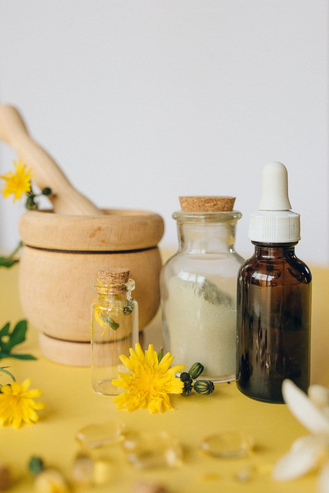 Wooden mortar, glass bottles and yellow flowers