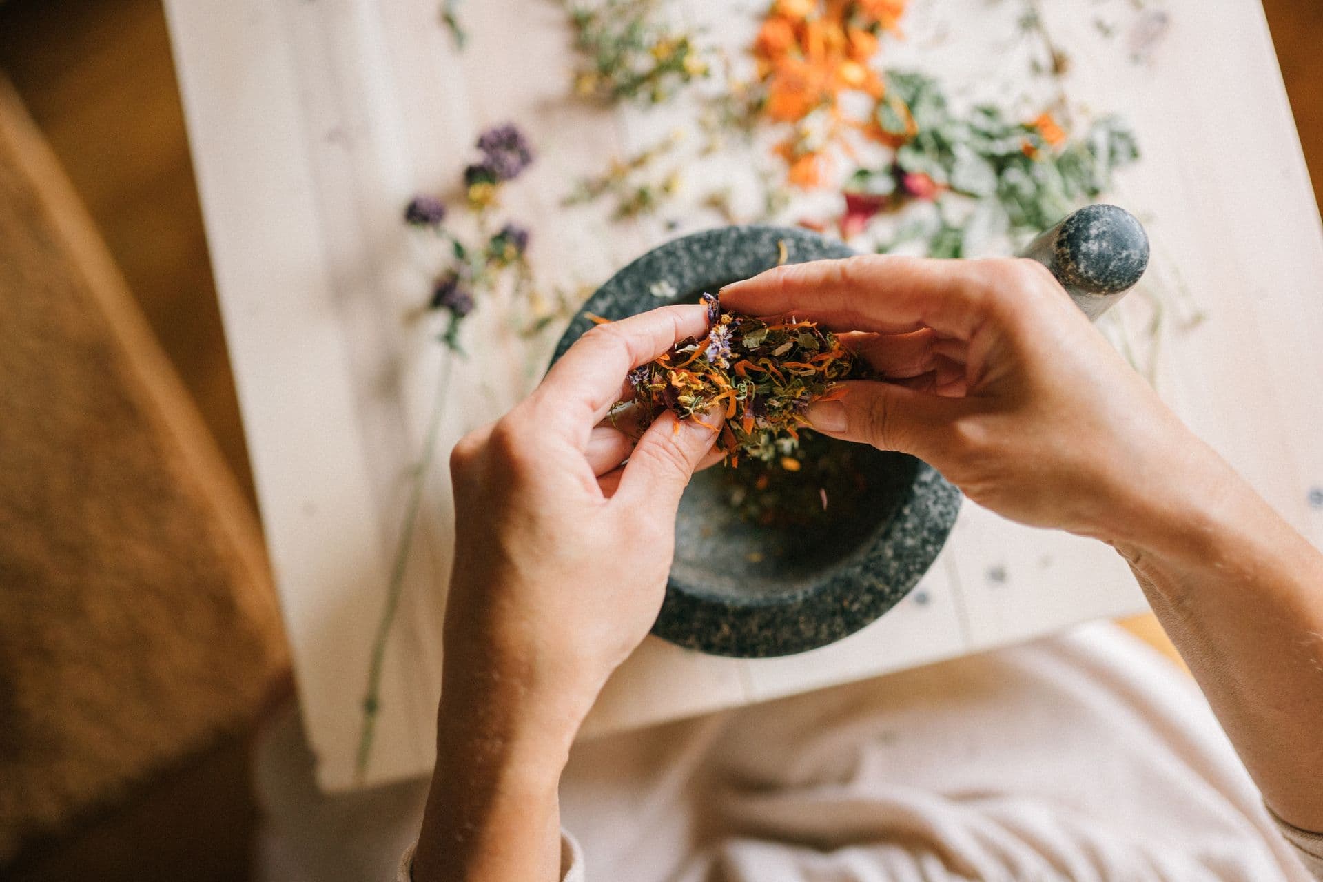 Hands mixing dried herbs in a mortar