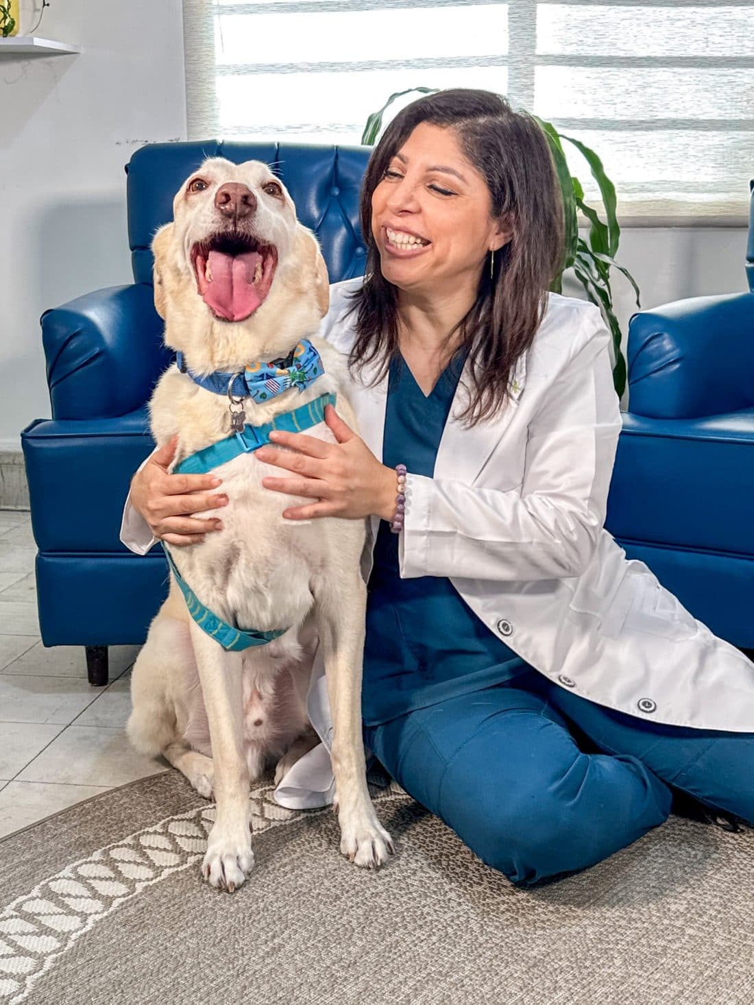 Rosy sitting on the clinic floor, hugging a white dog